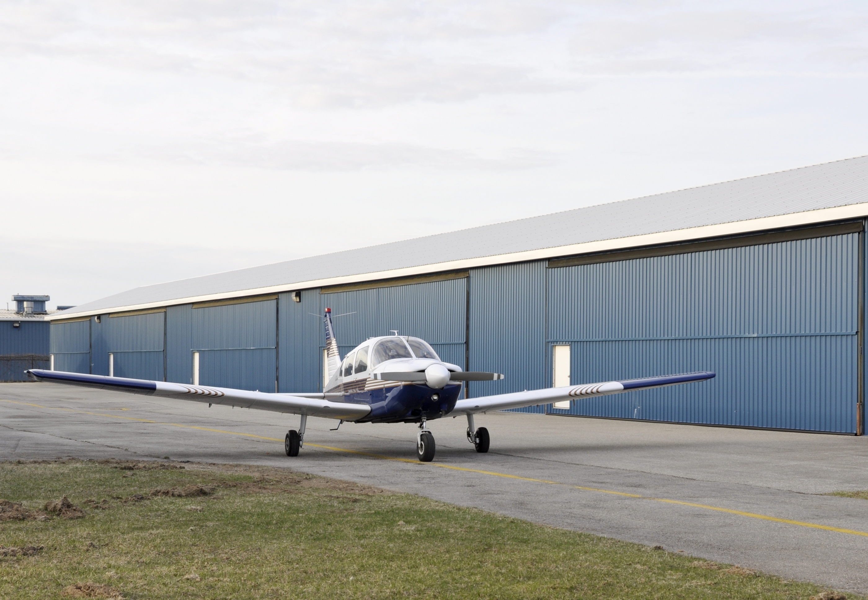 small airplane next to blue hangar