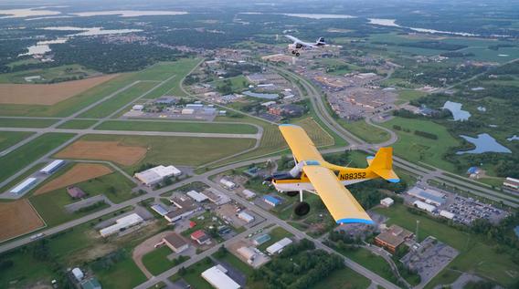 Aerial view of two prop planes flying over a small town