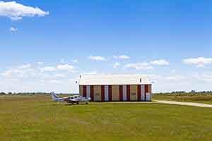 photo of airfield and small airplane with short mowed grass